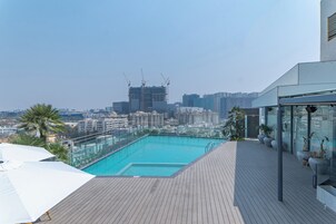 A rooftop pool with a city view, wooden deck, and modern architecture.