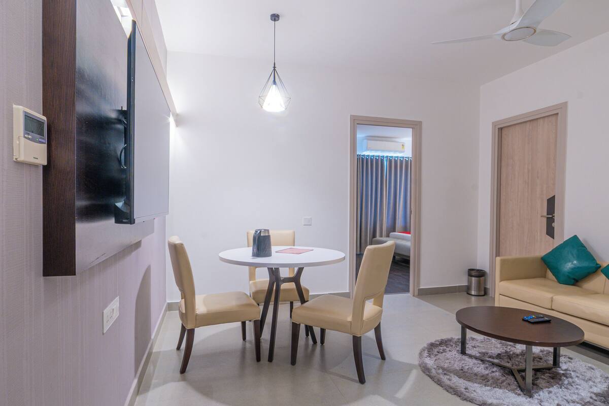 Una sala moderna con comedor, un sofá, una mesa de centro y un televisor montado en la pared.