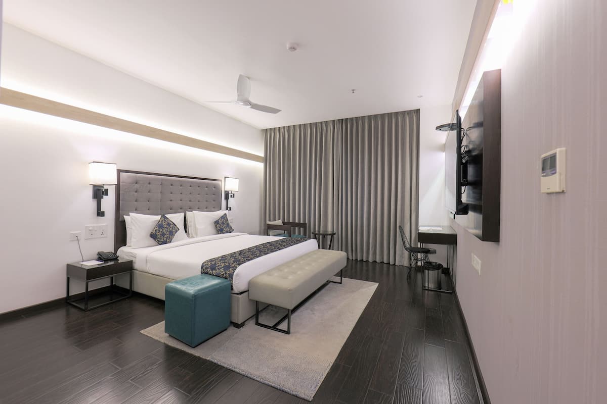 Una habitación de hotel moderna con una cama grande, un banco, un escritorio y un ventilador de techo.