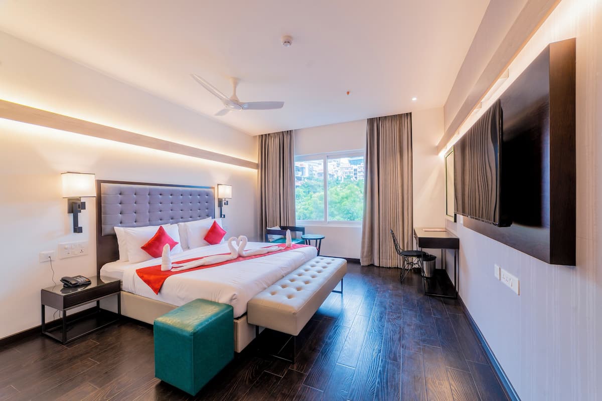 Habitación de hotel moderna con una cama grande, un televisor de pantalla plana, un escritorio y vistas al exterior.