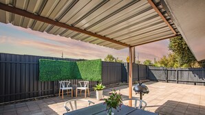 Un patio techado con una mesa, sillas y una parrilla.