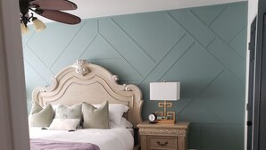 Un dormitorio con cama, mesita de noche, lámpara y velador.