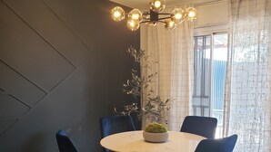 Un comedor con una mesa redonda, sillas azules, una araña y una planta en maceta.