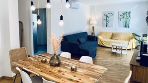 A modern living room with a wooden dining table, blue and yellow sofas, and a wooden floor. - Mediterranean apartment centrally located 500m beach (Sant Feliu de Guíxols)