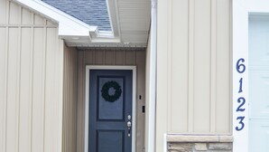 A house with a front door, a stone accent wall, and a garage door with the number 6123.