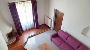 Ein Wohnzimmer mit einem violetten Sofa, einem Glastisch, einem Kamin und einer Treppe.