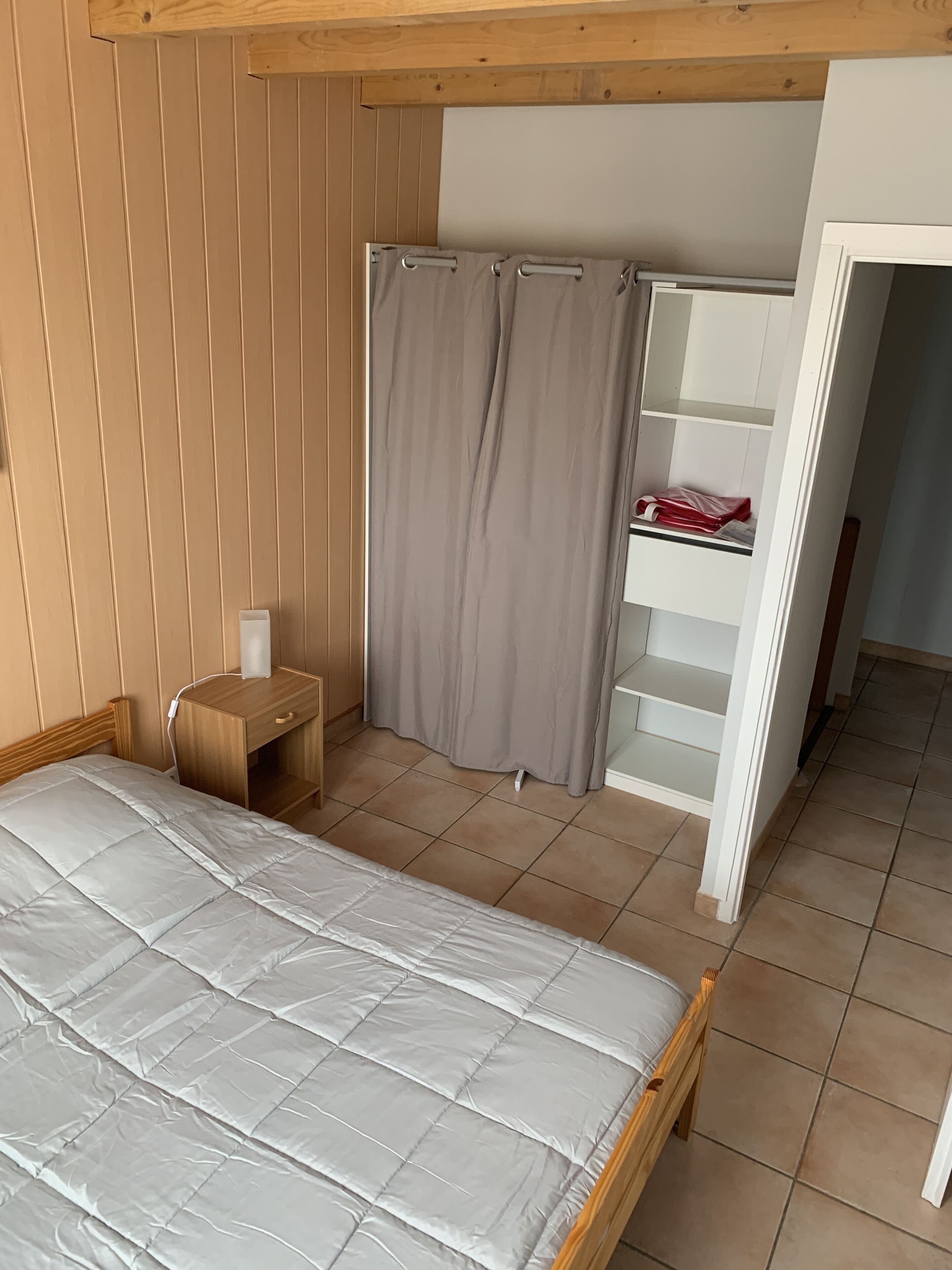 Un dormitorio con cama, mesita de noche, armario y cortina de ducha.