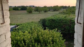 A view from a balcony with a brick wall and tiled floor, overlooking a grassy field with trees and a distant hill. - Gîte Caramolle, St Denis, Gard, Cévennes, 2 bedrooms, swimming pool, nature (Saint-Denis)