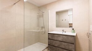 Un bagno moderno con doccia vetrata, un mobile lavabo con specchio e un lavandino.