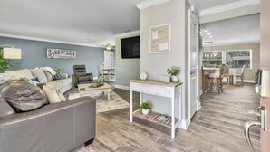 A living room with a grey sofa, a coffee table, and a dining area with a white table and chairs. - Beautiful Waterfront Pool Home | Close to Golf & Beaches | Dog Friendly | Free Wifi | Dock (Palm Coast)