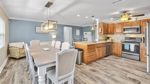 A modern kitchen with wooden cabinets, stainless steel appliances, and a dining area with a table and chairs. - Beautiful Waterfront Pool Home | Close to Golf & Beaches | Dog Friendly | Free Wifi | Dock (Palm Coast)
