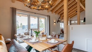 A dining area with a wooden table set for four, a sofa, and a view of the outdoors. - Luxurious chalet with sauna, near the ski slope (Turracher Höhe)