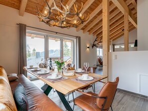 A dining area with a wooden table set for four, a sofa, and a view of the outdoors. - Luxurious chalet with sauna, near the ski slope (Turracher Höhe)
