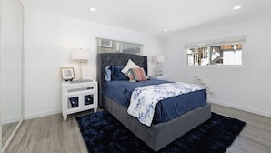 A bedroom with a bed, nightstands, a window, and a view of the outside. - Cheerful and Remodeled 3-bedroom beach cottage, STEPS to beach. Sleeps 9!  (Carlsbad)