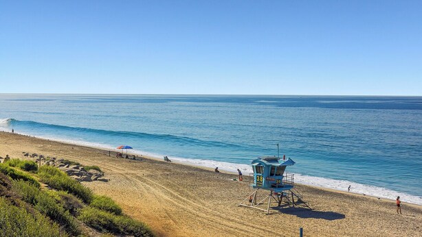 A beach with a lifeguard tower, clear blue water, and a sandy shore. - Cheerful and Remodeled 3-bedroom beach cottage, STEPS to beach. Sleeps 9!  (Carlsbad)