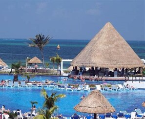 A resort pool area with thatched-roof structures, lounge chairs, and a view of the ocean. - **ATLANTIS BAHAMAS, PARADISE** - BEAUTIFUL 1 BEDROOM, SLEEPS 4+  (Paradise Island)