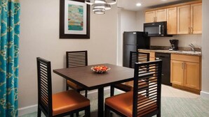 A compact kitchen with wooden cabinets, a black refrigerator, and a microwave. There is a dining table with chairs and a bowl of fruit. - **ATLANTIS BAHAMAS, PARADISE** - BEAUTIFUL 1 BEDROOM, SLEEPS 4+  (Paradise Island)