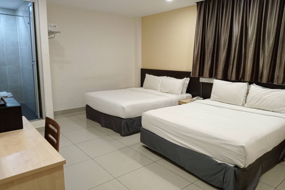 Hotellihuone, jossa on kaksi sänkyä, työpöytä ja tuoli.