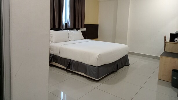 Una habitación de hotel moderna con una cama bien hecha, una mesita de noche, una lámpara y un armario.