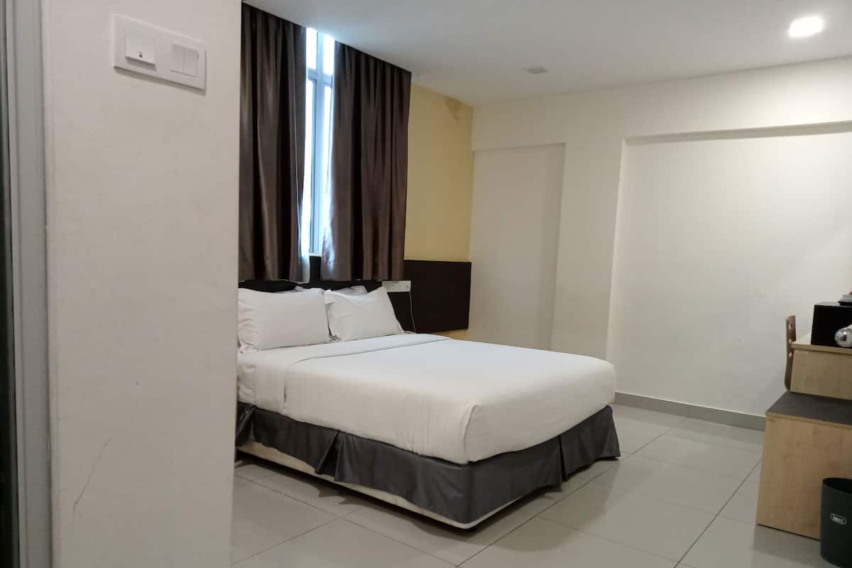 Moderni hotellihuone, jossa on siististi pedattu sänky, yöpöytä, lamppu ja vaatekaappi.