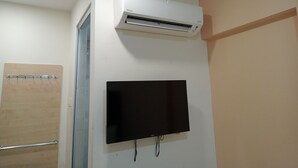 Una habitación con aire acondicionado instalado, un televisor de pantalla plana y una puerta de madera.