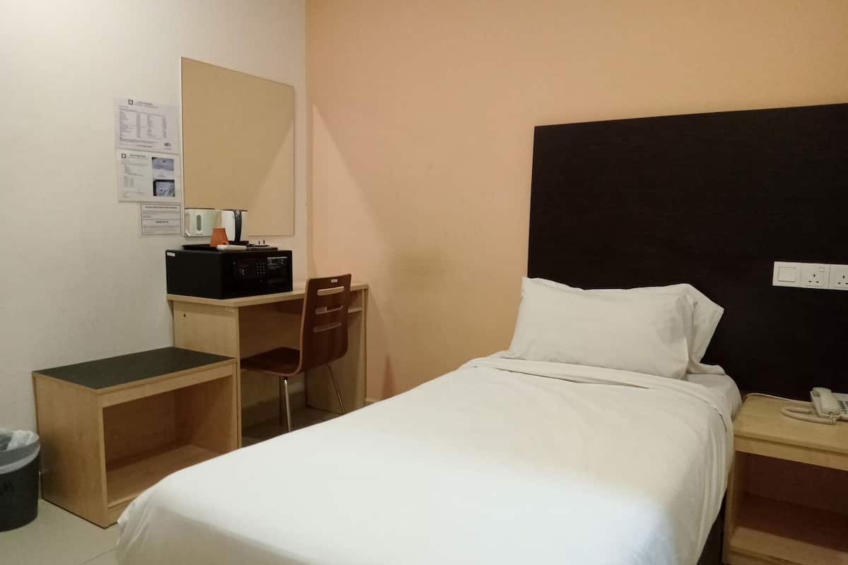 Hotellihuone, jossa on sänky, työpöytä, tuoli, puhelin ja roskakori.