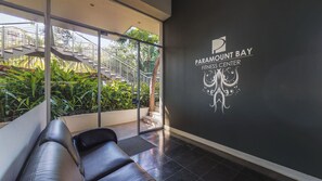 A fitness center with a logo, a staircase, and a seating area.