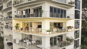 Un edificio residencial de varios pisos con balcones, mobiliario exterior y plantas en macetas.