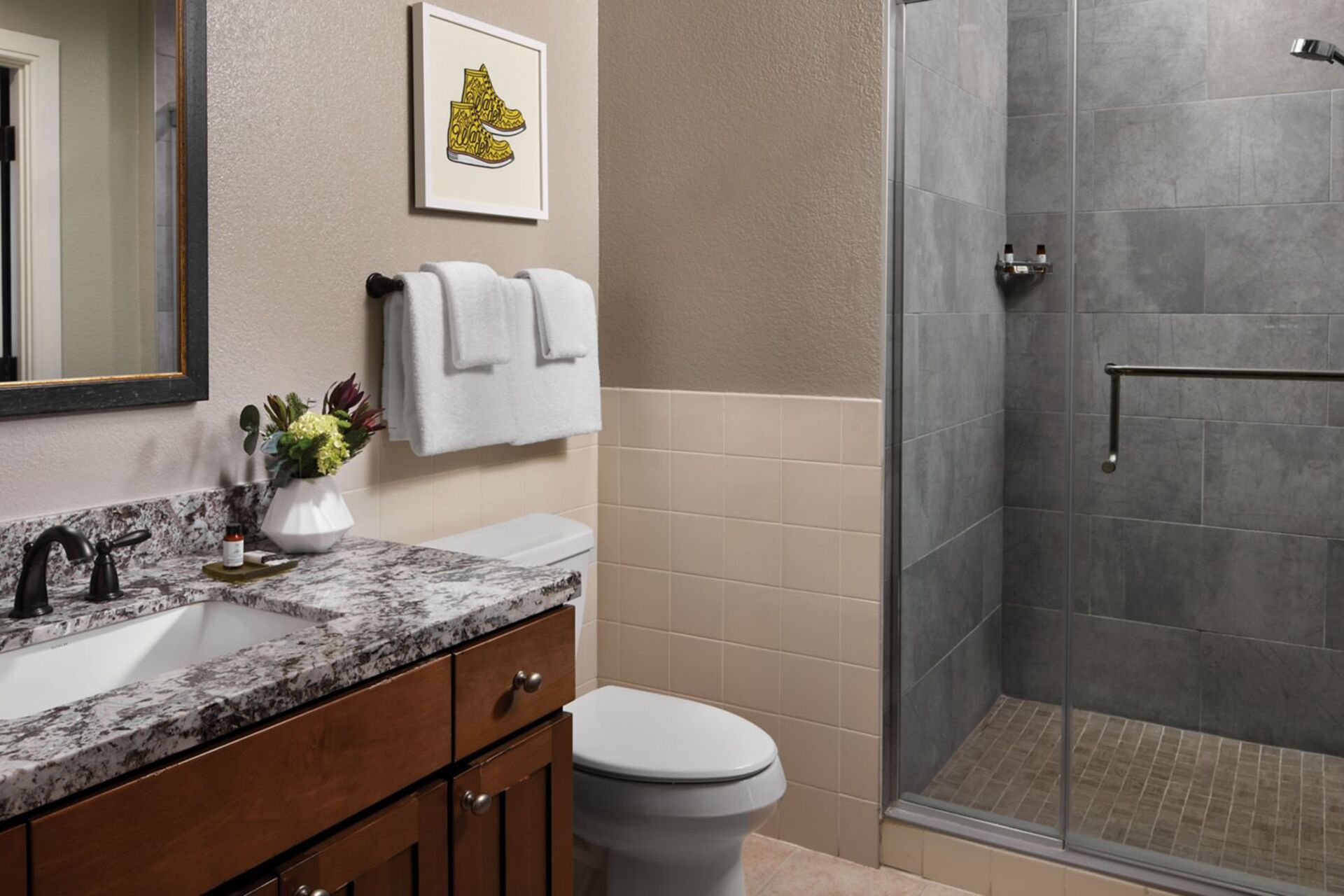 A bathroom with a marble sink, a toilet, and a glass-enclosed shower.