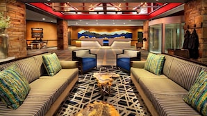 A lobby with a reception desk, two sofas with patterned cushions, a coffee table, and a mural on the wall. - Marriott MountainSide - Ski-In & Ski-Out - Enjoy Full Resort Access - Sleeps 8 (Park City)