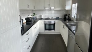 Una cocina moderna con armarios blancos, encimera negra y electrodomésticos de acero inoxidable.