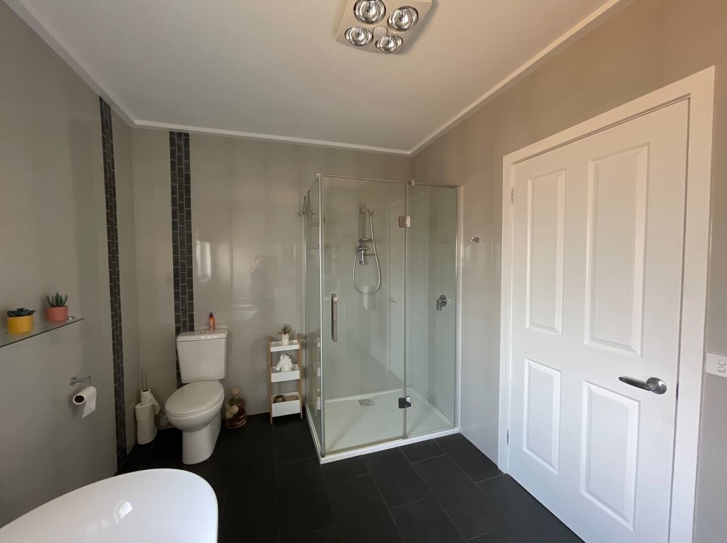 Ein modernes Badezimmer mit einer einteiligen Duschkabine, einer Toilette und einem weißen Waschbecken.