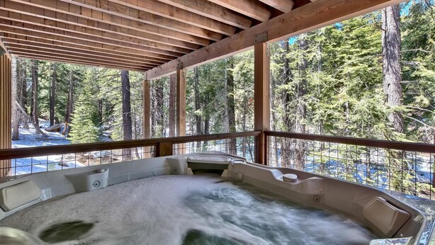 A hot tub in a wooden cabin with a view of a forest.
