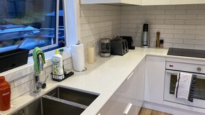 Eine moderne Küche mit weißen Schränken, einer Edelstahlspüle, einer Kaffeemaschine und einem Toaster.