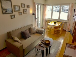 En hyggelig stue med en sofa, et lille bord og et spiseområde med bord og stole.