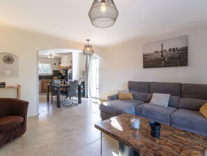A modern living room with a grey sofa, a wooden coffee table, and a dining area with a kitchen in the background. - Villa Vaccaja by Interhome (Porto Vecchio)