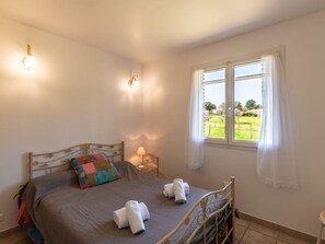 A bedroom with a bed, a window with a view of a green landscape, and a bedside lamp. - Les Rosiers by Interhome (Porto Vecchio)