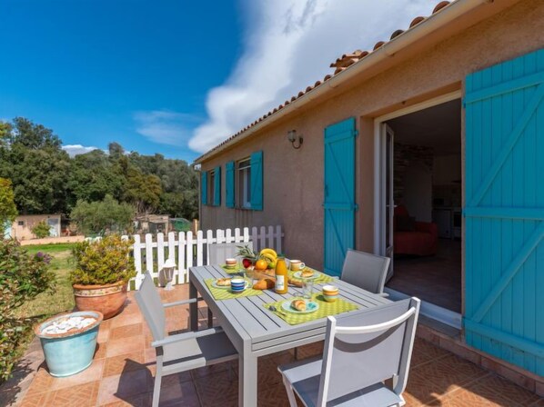 A patio with a table set for breakfast, a white fence, and a blue door. - Les Rosiers by Interhome (Porto Vecchio)