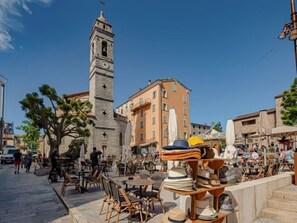 A square with outdoor seating, a clock tower, and a market stall selling hats. - Les Rosiers by Interhome (Porto Vecchio)