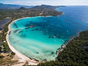 An aerial view of a coastal area with a beach, clear turquoise waters, and scattered boats. - Les Rosiers by Interhome (Porto Vecchio)