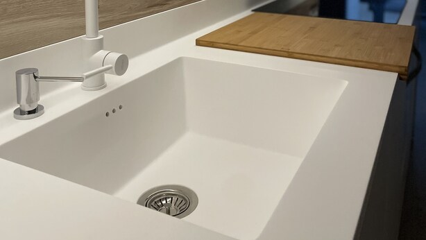 Eine moderne Küche mit weißem Spülbecken, Edelstahlarmatur und Holz Arbeitsplatte.