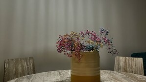 Ein Essbereich mit einem runden Tisch, einer Blumenvase und einer Hängeleuchte.