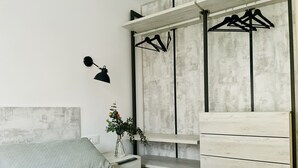 Ein modernes Schlafzimmer mit Bett, Nachttisch, Kommode und einer Wandkleiderstange.