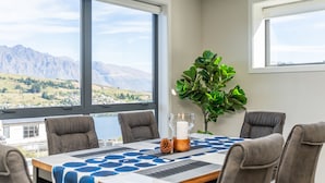 A dining area with a table set for four, large windows offering a mountain view, and a potted plant on the table.
