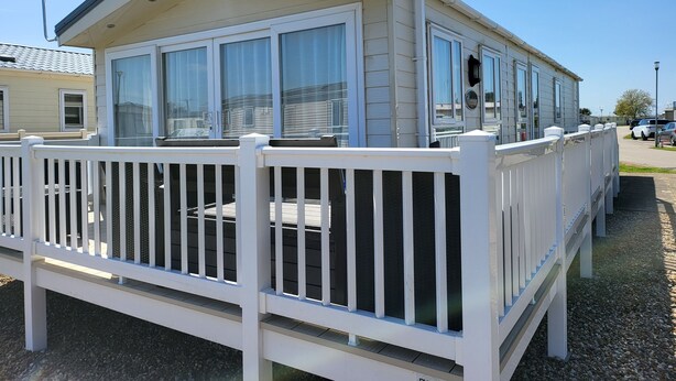 A mobile home with a white exterior, large windows, and a white deck. - 2br-sleeps6-fireplace-parking-patio-seaside (Clacton-on-Sea)