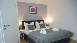 A neatly made bed with pillows, a bedside table with a lamp, and a framed picture on the wall. - SILONCE Hotels & Restaurant (Radevormwald)