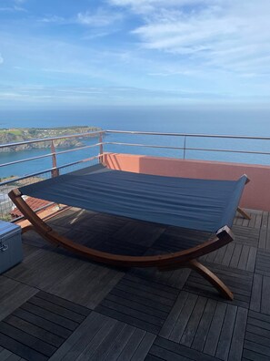 A hammock on a wooden deck with a view of the ocean and distant land. - Exceptional sea view apartment (Cerbère)