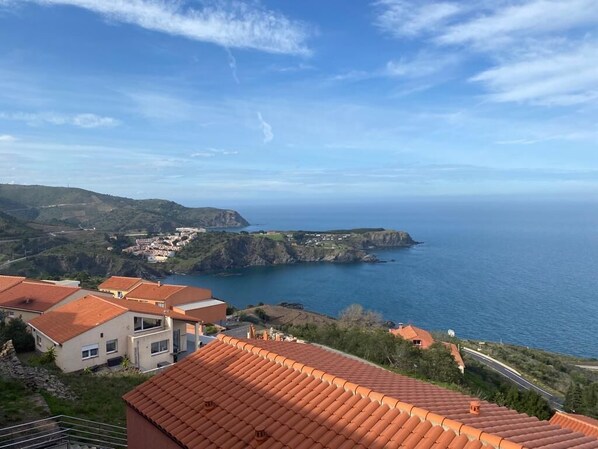 A coastal view with terracotta-roofed buildings overlooking the sea.