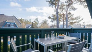 A deck with a table and chairs, a bowl of fruit, and a vase. - Upper floor apartment Lee West 2.3 (Ostseebad Dierhagen)