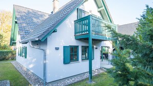 A white house with green shutters, a balcony, and a sloped roof. - Upper floor apartment Lee West 2.3 (Ostseebad Dierhagen)